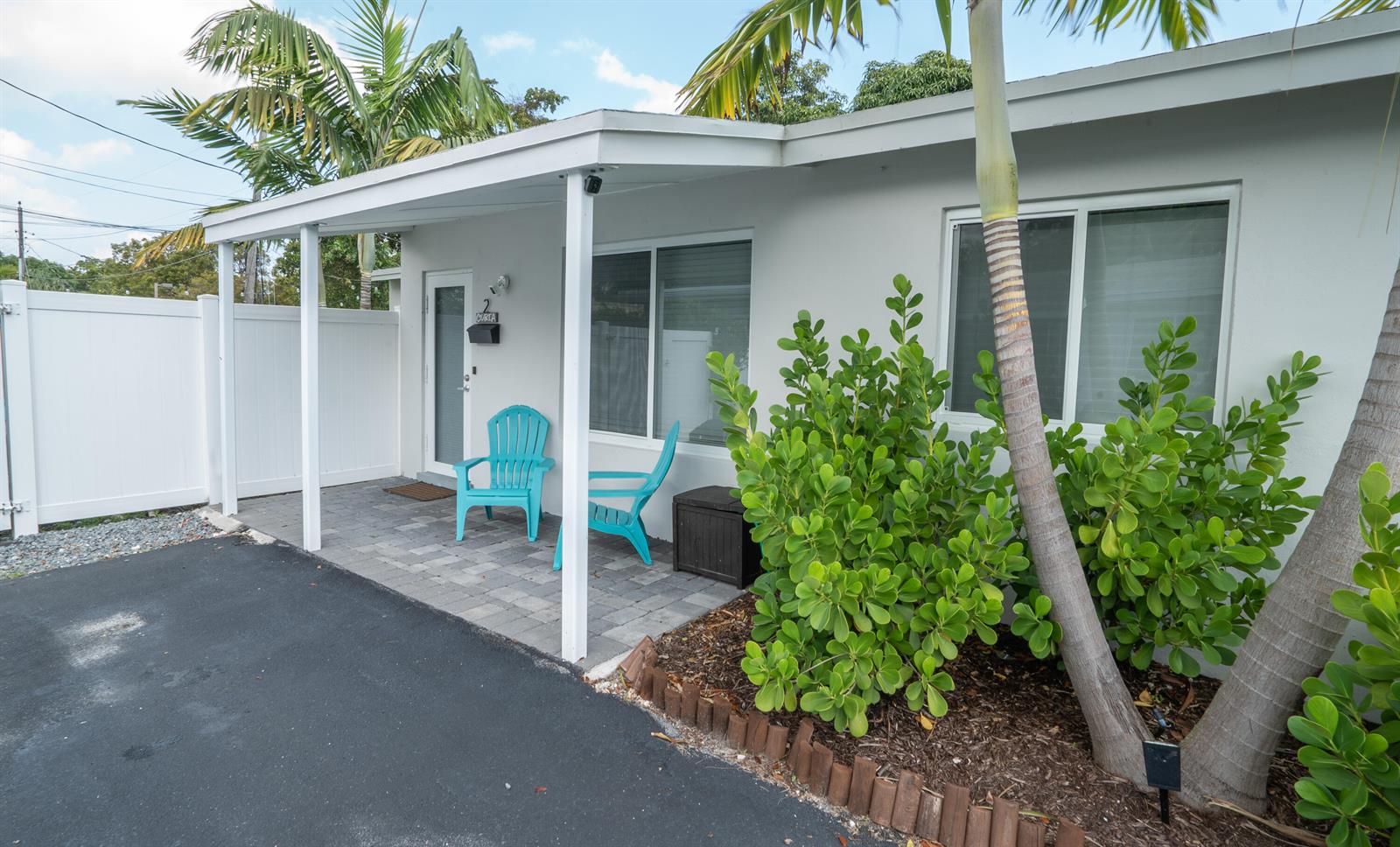 A white exterior building features a covered patio with two turquoise chairs and palm trees — 1909 NE 2nd Street Unit 2, Pompano Beach FL 33060, POMPANO BEACH, FL