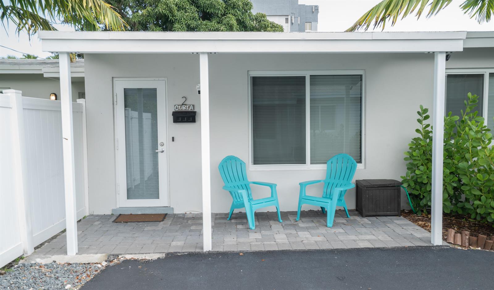 A white building exterior features a paved patio with two turquoise chairs and a door — 1909 NE 2nd Street Unit 2, Pompano Beach FL 33060, POMPANO BEACH, FL