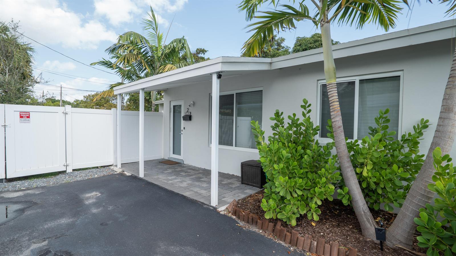 A white single-story building features a covered patio, paved walkway, and palm trees — 1909 NE 2nd Street Unit 2, Pompano Beach FL 33060, POMPANO BEACH, FL
