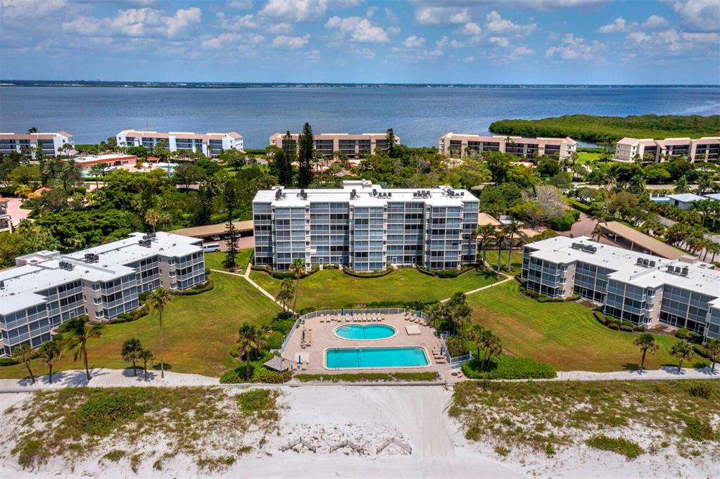 An aerial view of a multi-story apartment complex with a pool near the beach — 4825 GULF OF MEXICO DRIVE UNIT 105, LONGBOAT KEY, FL