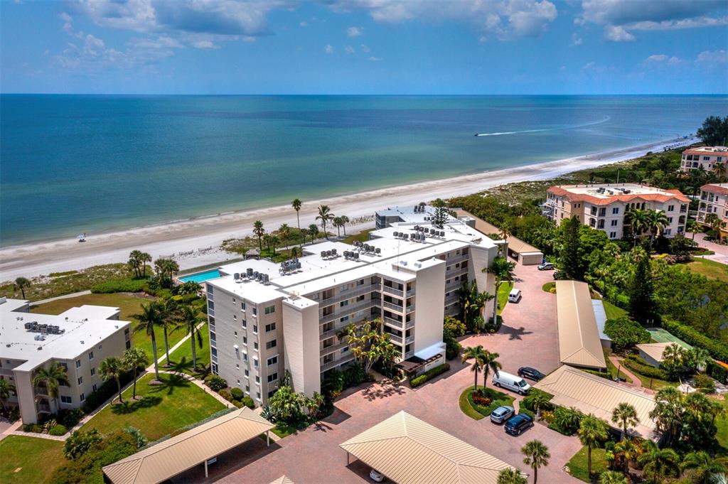 An aerial view shows a multi-story apartment building located directly on a sandy beach — 4825 GULF OF MEXICO DRIVE UNIT 105, LONGBOAT KEY, FL