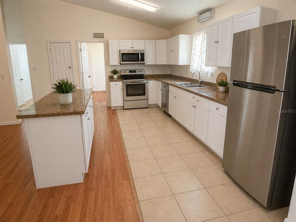 A kitchen with white cabinets, stainless steel appliances, granite countertops, and a center island — 1446 NW MAGNOLIA TERRACE, ARCADIA, FL