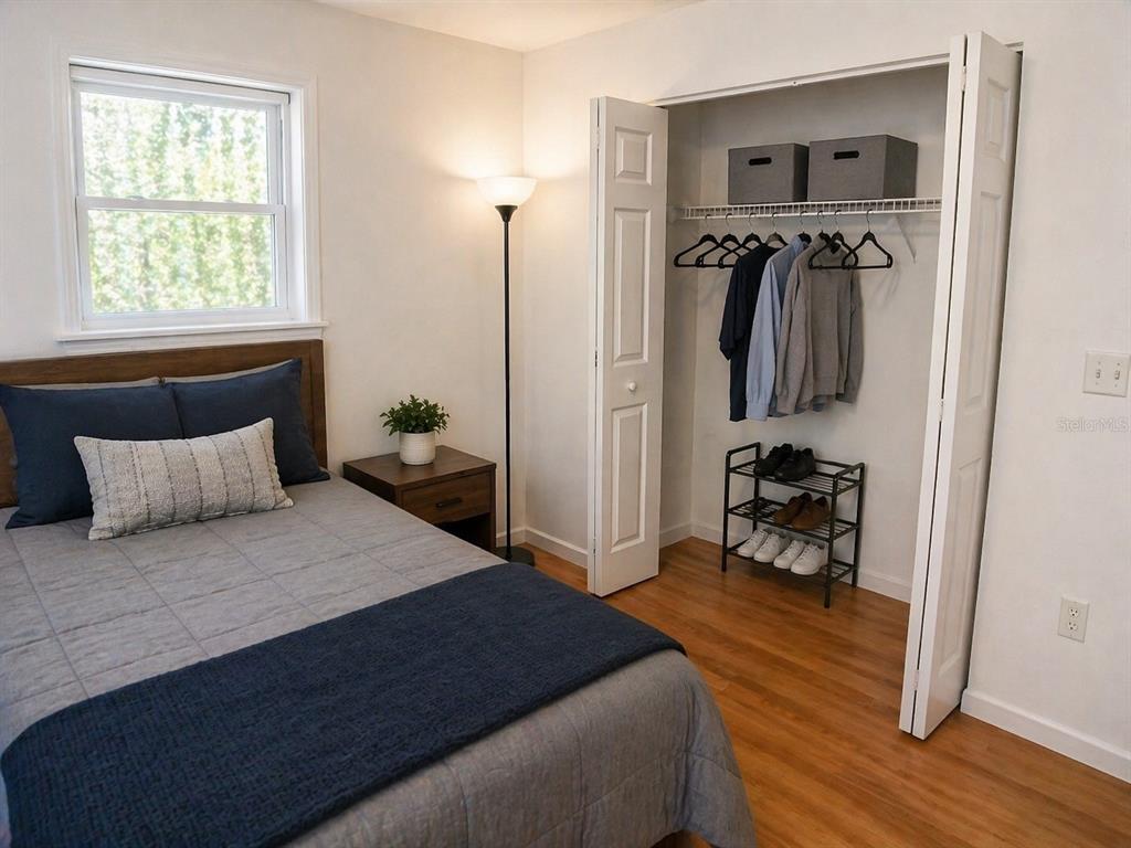 A bedroom features a bed, a nightstand, a floor lamp, and an open closet — 1446 NW MAGNOLIA TERRACE, ARCADIA, FL