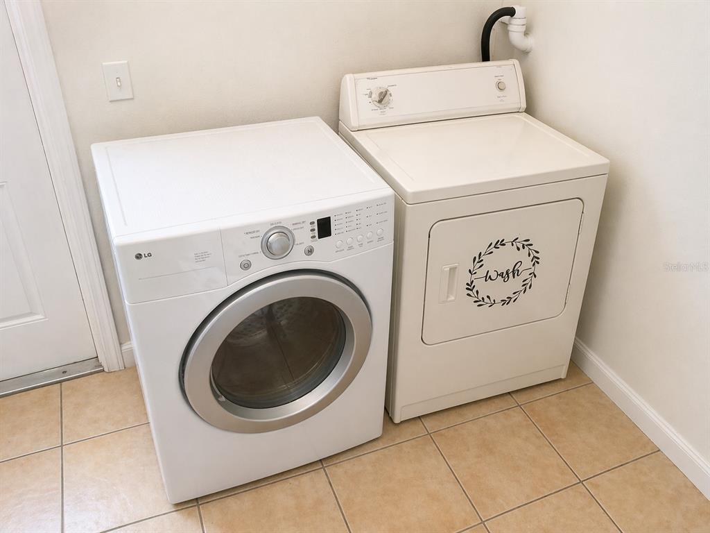 A laundry room features a white front-loading LG dryer next to a white top-loading washer — 1446 NW MAGNOLIA TERRACE, ARCADIA, FL