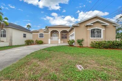A tan, single-story suburban house with a concrete driveway and a grassy front yard — 7380 PEBBLE BEACH LANE, SEMINOLE, FL