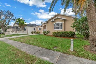 A tan single-story house with a front lawn and a sidewalk under a blue sky — 7380 PEBBLE BEACH LANE, SEMINOLE, FL