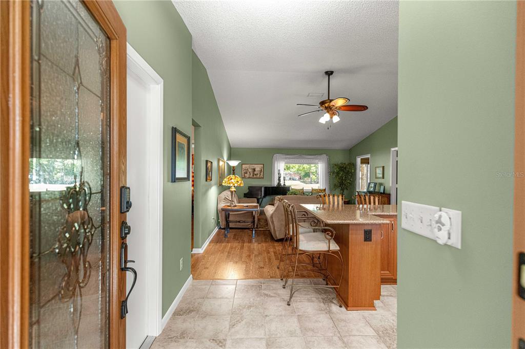 A view from a doorway into an open-concept living area with green walls and tile — 9380 SW 84TH TERRACE UNIT C, OCALA, FL