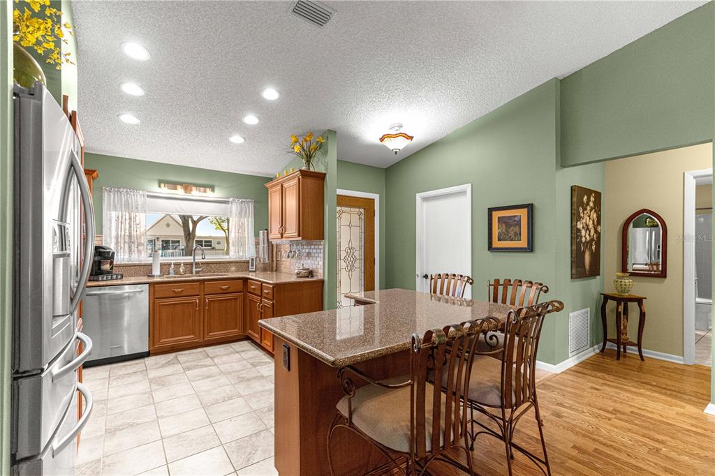 A kitchen with wood cabinets, granite countertops, a center island, and green walls — 9380 SW 84TH TERRACE UNIT C, OCALA, FL