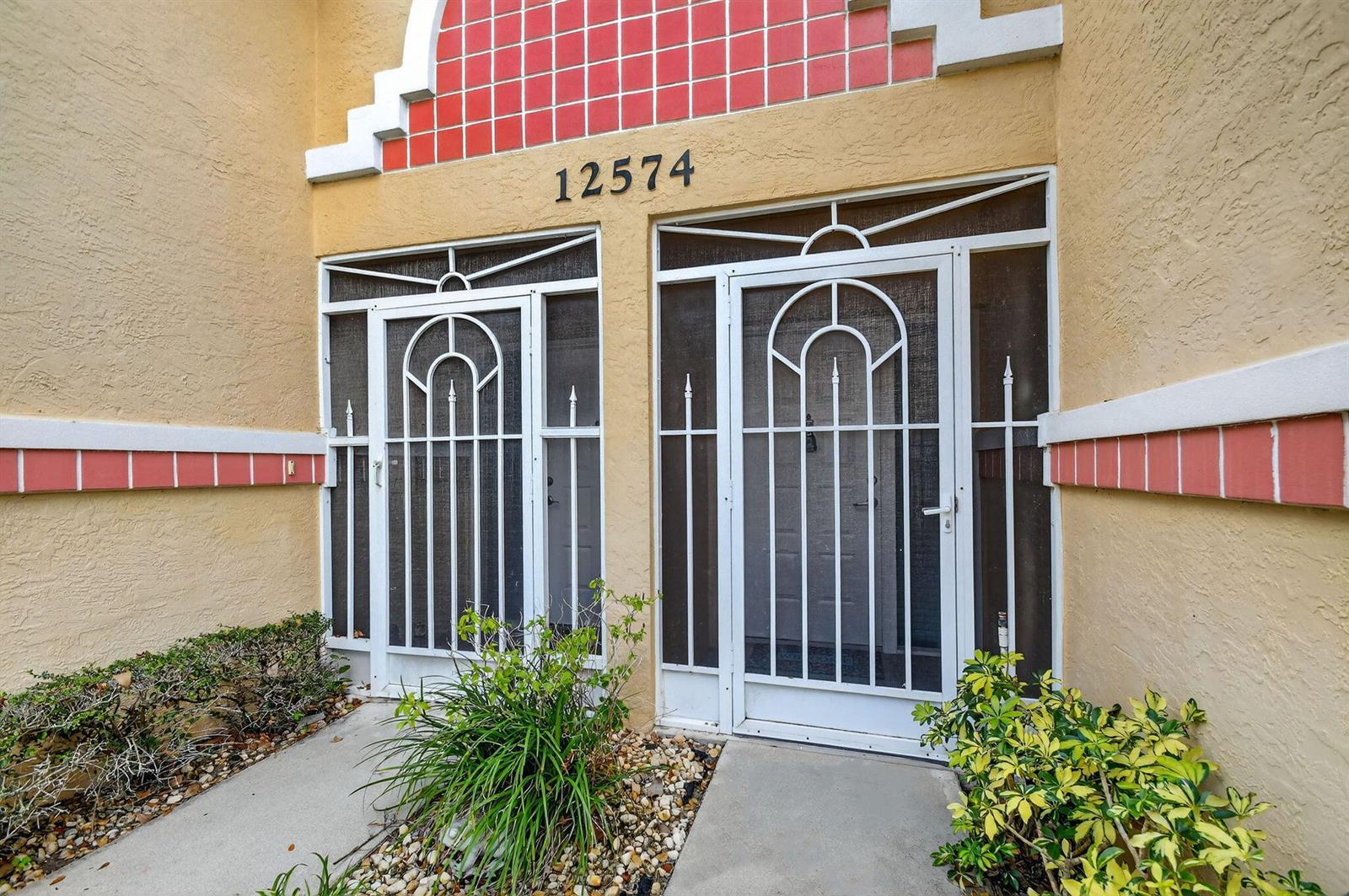 The exterior entrance features two white screen doors beneath a decorative red-tiled archway — 12574 Crystal Pointe Drive # C, Boynton Beach FL 33437, BOYNTON BEACH, FL