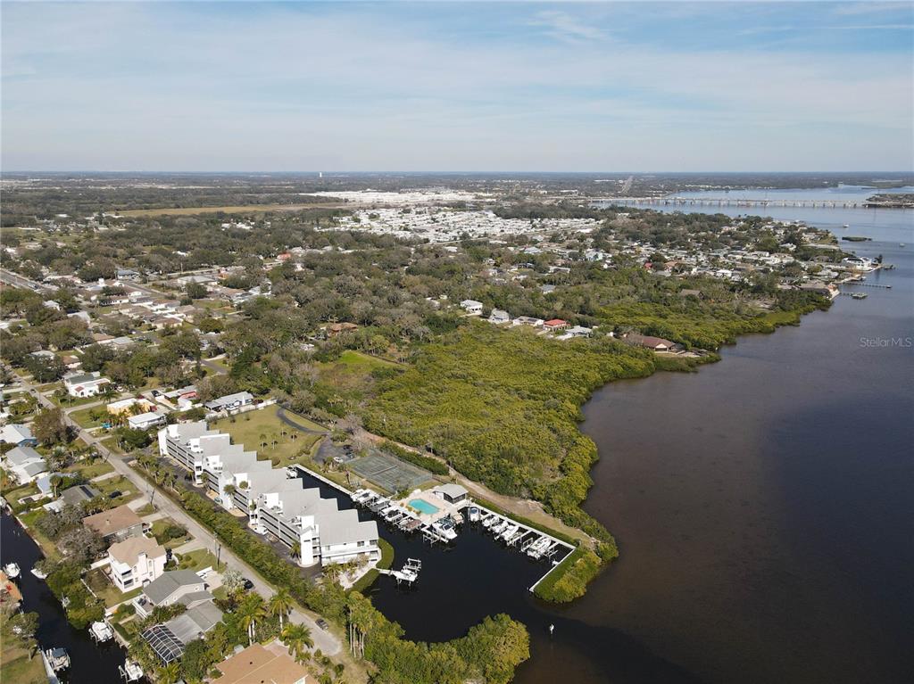 An aerial view shows a waterfront condominium complex with a pool and boat slips — 515 LEFFINGWELL AVENUE UNIT 116, ELLENTON, FL