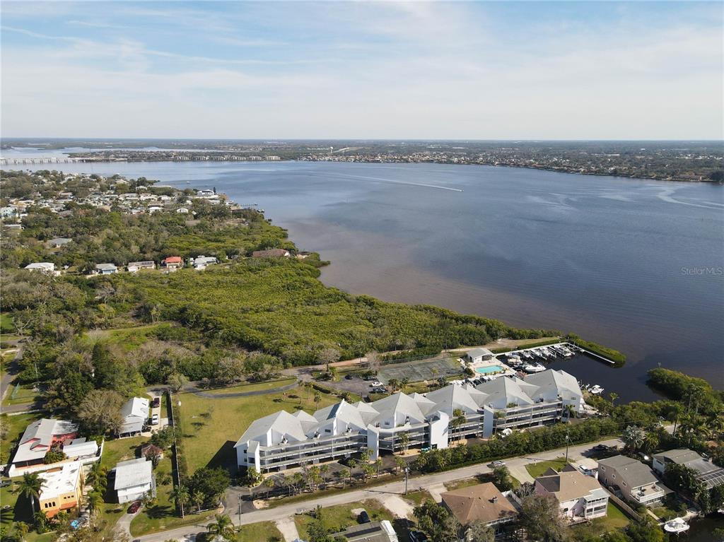 An aerial view shows a multi-story waterfront apartment complex with a pool and boat slips — 515 LEFFINGWELL AVENUE UNIT 116, ELLENTON, FL