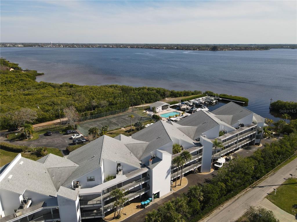 An aerial view shows a multi-story waterfront condominium complex with a pool and boat slips — 515 LEFFINGWELL AVENUE UNIT 116, ELLENTON, FL