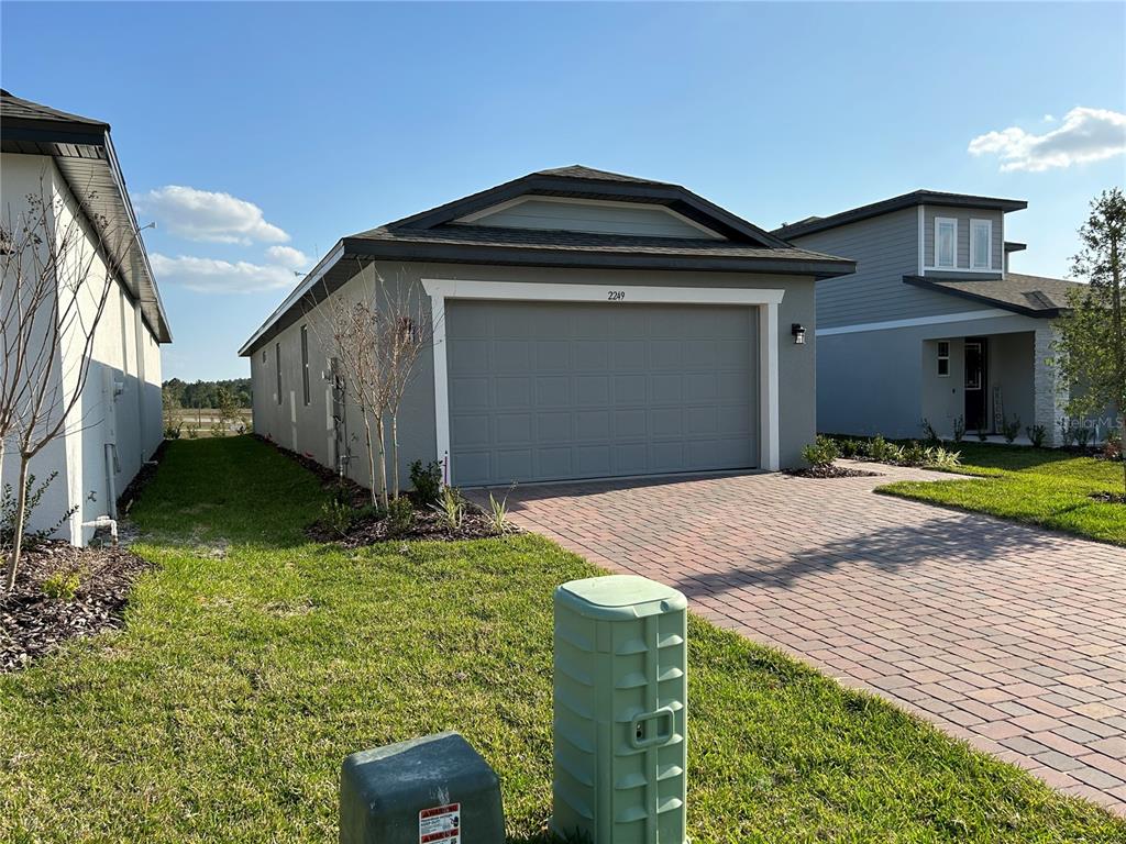 A single-story house with a gray garage door and a paved driveway — 2249 MYSTIC MAZE LANE, CLERMONT, FL