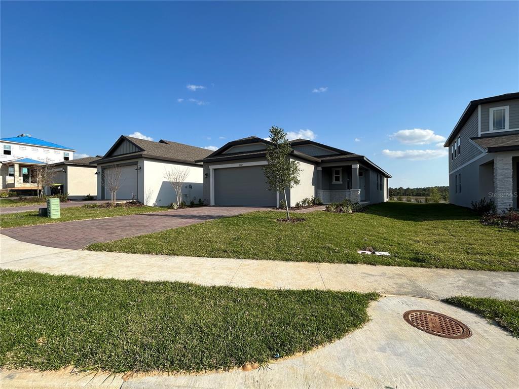 A street-level view of a single-story suburban house with a paved driveway and lawn — 2249 MYSTIC MAZE LANE, CLERMONT, FL