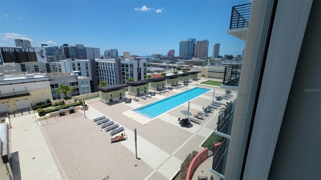 An elevated view of an outdoor swimming pool deck surrounded by apartment buildings and city skyline — 1120 E KENNEDY BOULEVARD UNIT 1217, TAMPA, FL