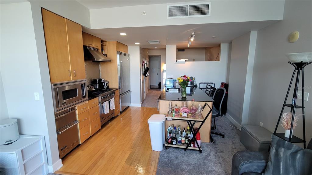 A kitchen with light wood cabinets, stainless steel appliances, and a central island with seating — 1120 E KENNEDY BOULEVARD UNIT 1217, TAMPA, FL