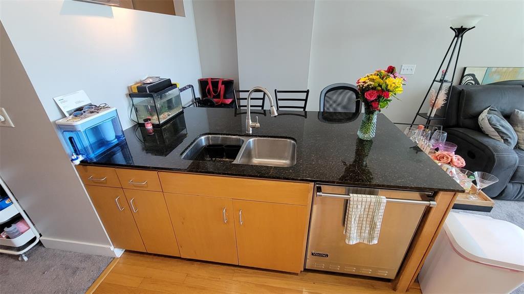 A kitchen island features a double-basin sink, dark granite countertops, and light wood cabinetry — 1120 E KENNEDY BOULEVARD UNIT 1217, TAMPA, FL