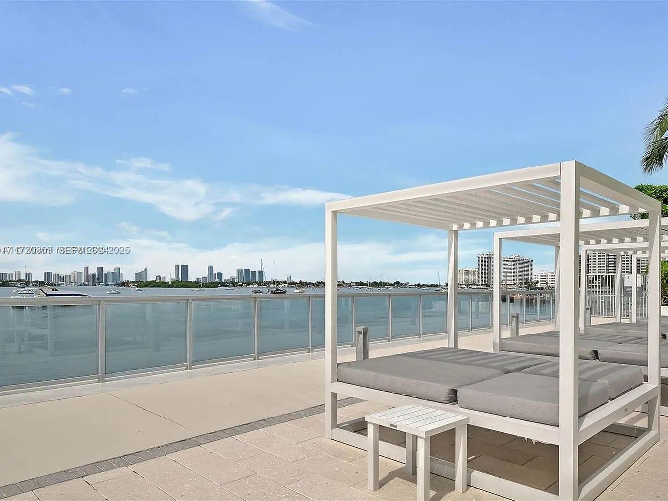 A white cabana with gray cushions sits on a paved patio overlooking a bay — 1000 West Ave, Miami Beach FL 33139, MIAMI BEACH, FL