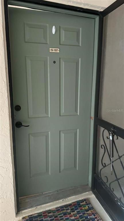 A sage green front door with a unit number sign and a black handle — 19505 QUESADA AVENUE UNIT S107, PORT CHARLOTTE, FL