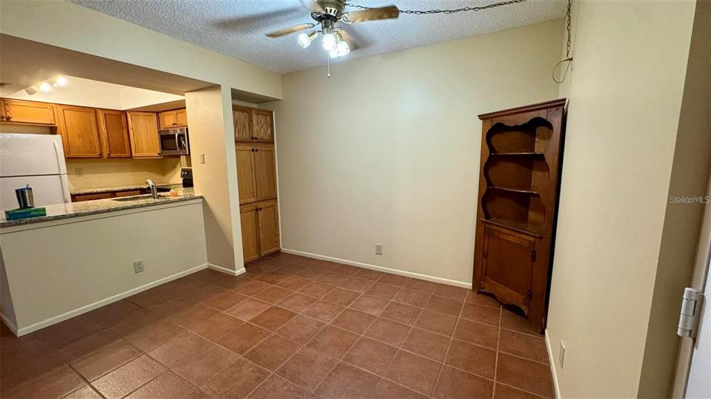 A dining area with tile flooring, a ceiling fan, and a wooden corner hutch — 19505 QUESADA AVENUE UNIT S107, PORT CHARLOTTE, FL
