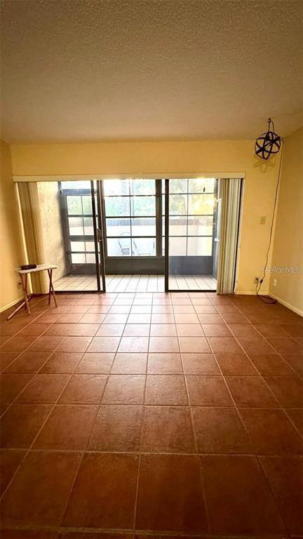 A room with terracotta tile flooring and large sliding glass doors leading to a patio — 19505 QUESADA AVENUE UNIT S107, PORT CHARLOTTE, FL