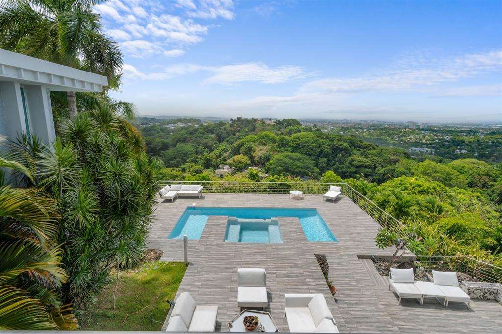 An elevated outdoor patio features a swimming pool, lounge seating, and panoramic views of greenery — 7 LA ROCA STREET BEVERLY HILLS, GUAYNABO, PR