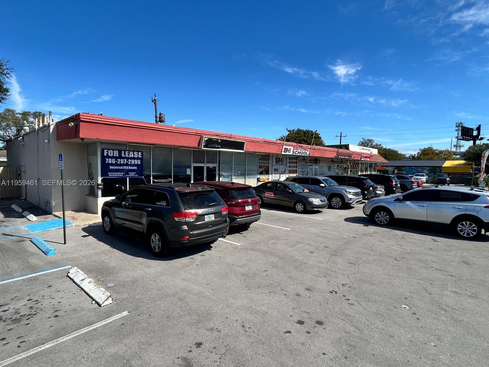 A commercial strip mall with a parking lot and several parked vehicles under a blue sky — 6339 Johnson St, Hollywood FL 33024, HOLLYWOOD, FL
