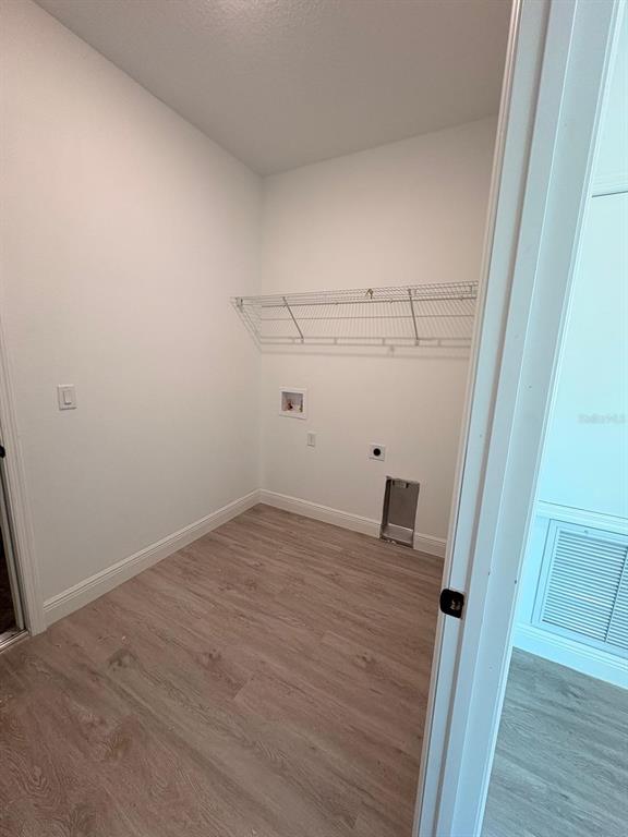 A laundry room with light wood-look flooring, white walls, and a wire shelving unit — 7838 N SARAZEN DRIVE, CITRUS SPRINGS, FL