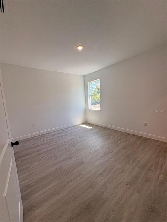 An empty bedroom features light-colored wood-look flooring, white walls, and a single window — 7838 N SARAZEN DRIVE, CITRUS SPRINGS, FL