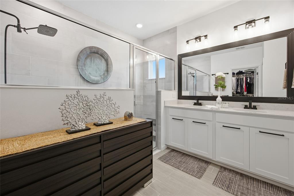 A bathroom with a dark wood dresser, white vanity, large mirror, and glass-enclosed shower — 8946 SW 67TH AVENUE, OCALA, FL