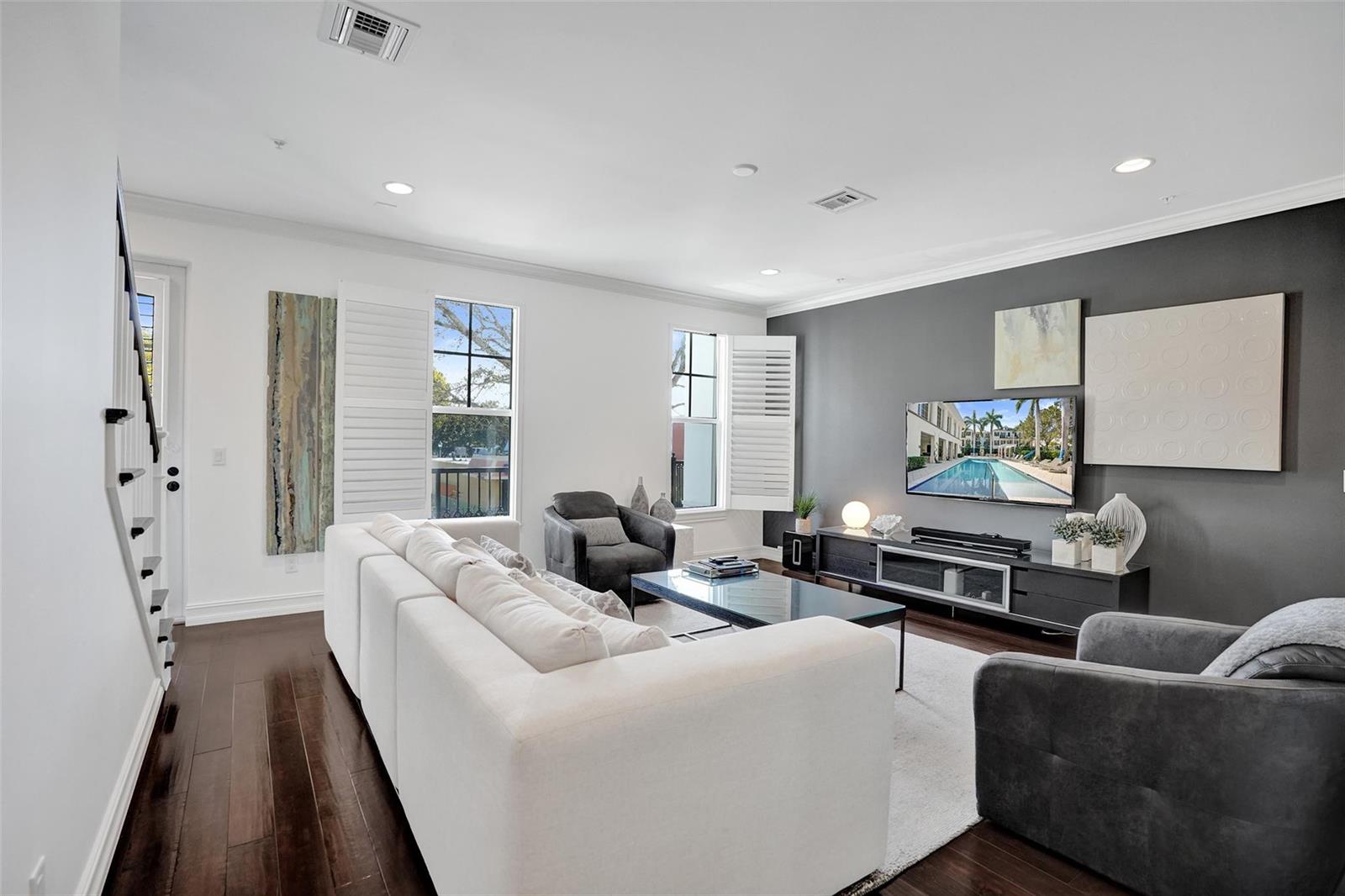 A living room features a white sectional sofa, dark gray accent wall, and hardwood floors — 381 E Cannery Row Circle, Delray Beach FL 33444, DELRAY BEACH, FL