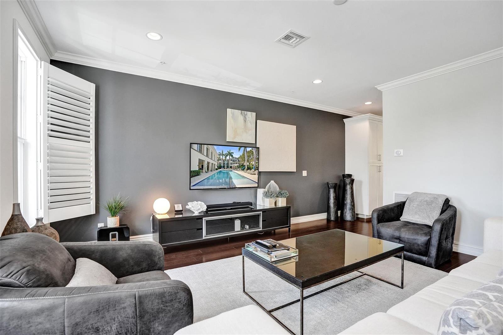 A living room features a dark gray accent wall, a television, and modern furniture — 381 E Cannery Row Circle, Delray Beach FL 33444, DELRAY BEACH, FL