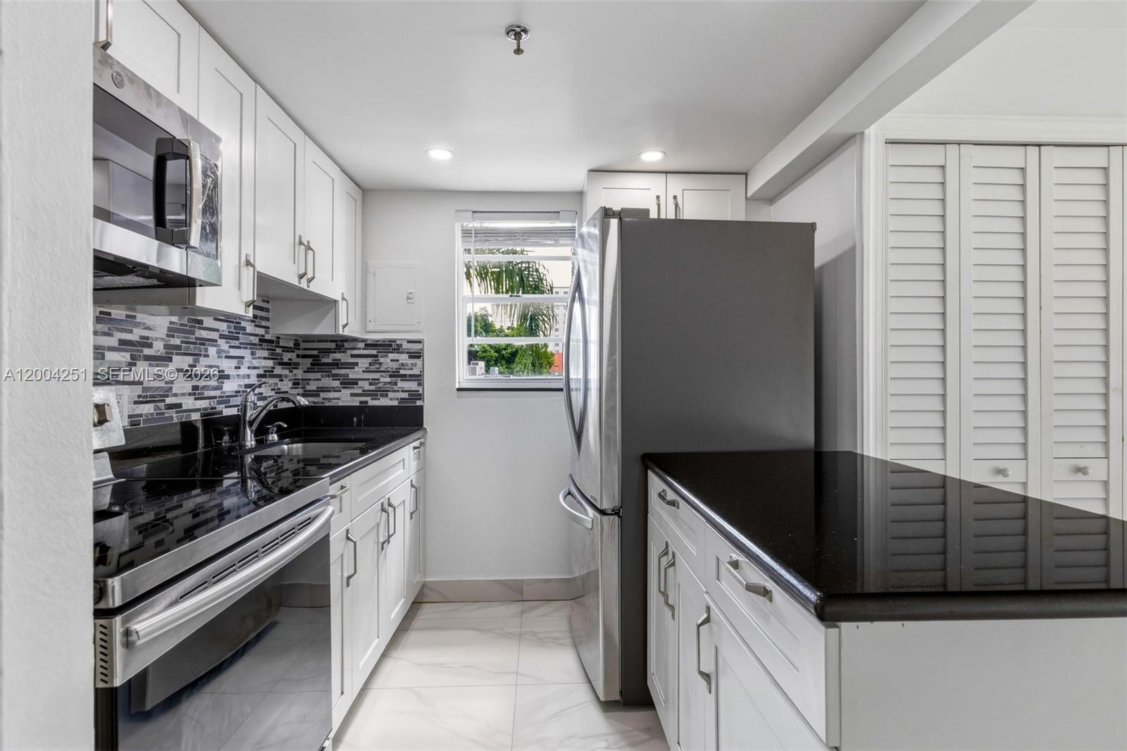 An empty room features white walls, marble-patterned tile flooring, a ceiling fan, and a balcony — 140 NW 14th Ave # 9, Miami FL 33125, MIAMI, FL