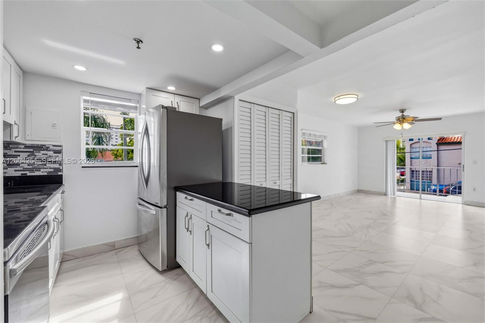 A living room with white marble-style tile floors, a ceiling fan, and a sliding glass door — 140 NW 14th Ave # 9, Miami FL 33125, MIAMI, FL