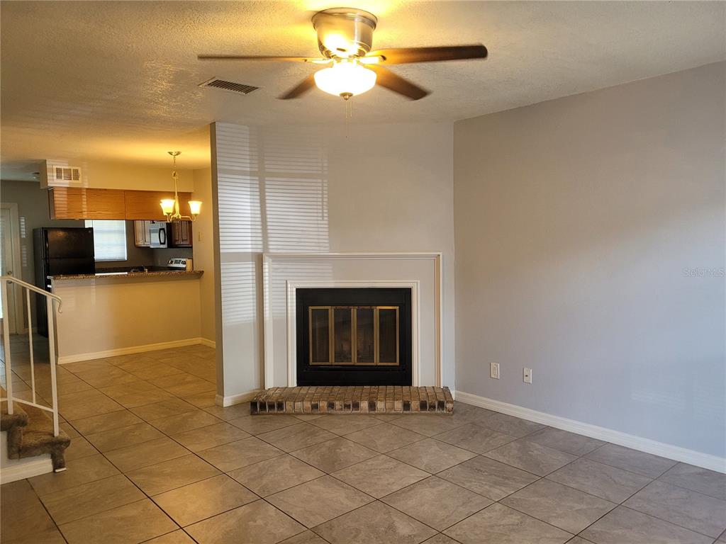A living room with tile flooring, a fireplace, and an adjacent kitchen area — 11301 GRANDVILLE DRIVE, TEMPLE TERRACE, FL