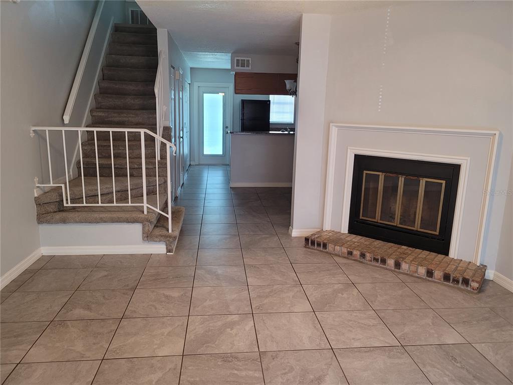 A living room features tile flooring, a fireplace with a brick hearth, and a carpeted staircase — 11301 GRANDVILLE DRIVE, TEMPLE TERRACE, FL