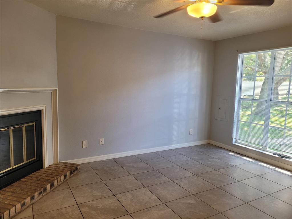 A living room features a fireplace, tile flooring, a ceiling fan, and a large window — 11301 GRANDVILLE DRIVE, TEMPLE TERRACE, FL