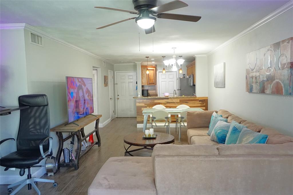 A living room with a sectional sofa, dining area, and kitchen visible in the background — 10122 WINSFORD OAK BOULEVARD UNIT 409, TAMPA, FL