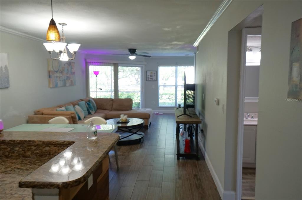 A living room features a sectional sofa, wood-look tile flooring, and an open kitchen counter — 10122 WINSFORD OAK BOULEVARD UNIT 409, TAMPA, FL