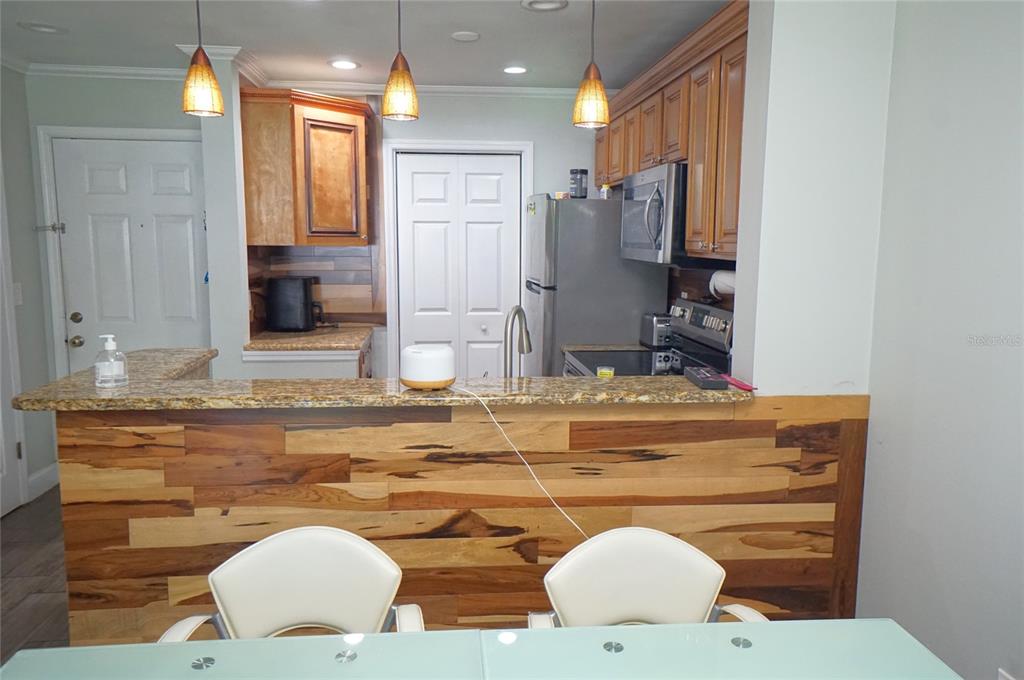 A kitchen features wood-paneled cabinetry, granite countertops, and a breakfast bar with wood-plank siding — 10122 WINSFORD OAK BOULEVARD UNIT 409, TAMPA, FL