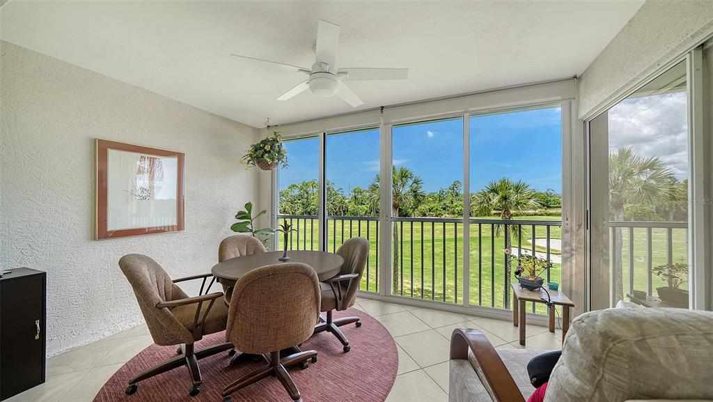 A sunroom with a dining set, tile floors, and large windows overlooking a golf course — 9641 CASTLE POINT DRIVE UNIT 1226, SARASOTA, FL