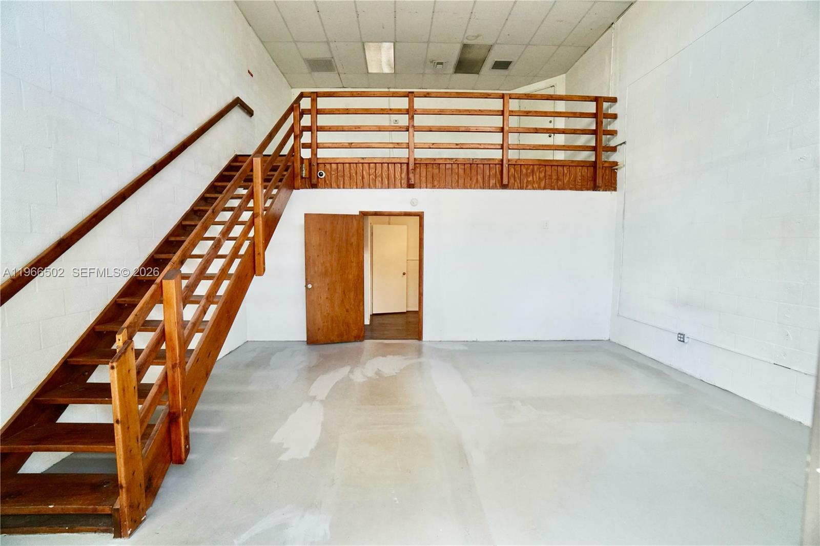 An industrial space features a wooden staircase leading to a mezzanine with a wooden railing — 12307 SW 132nd Ct # 4, Miami FL 33186, MIAMI, FL