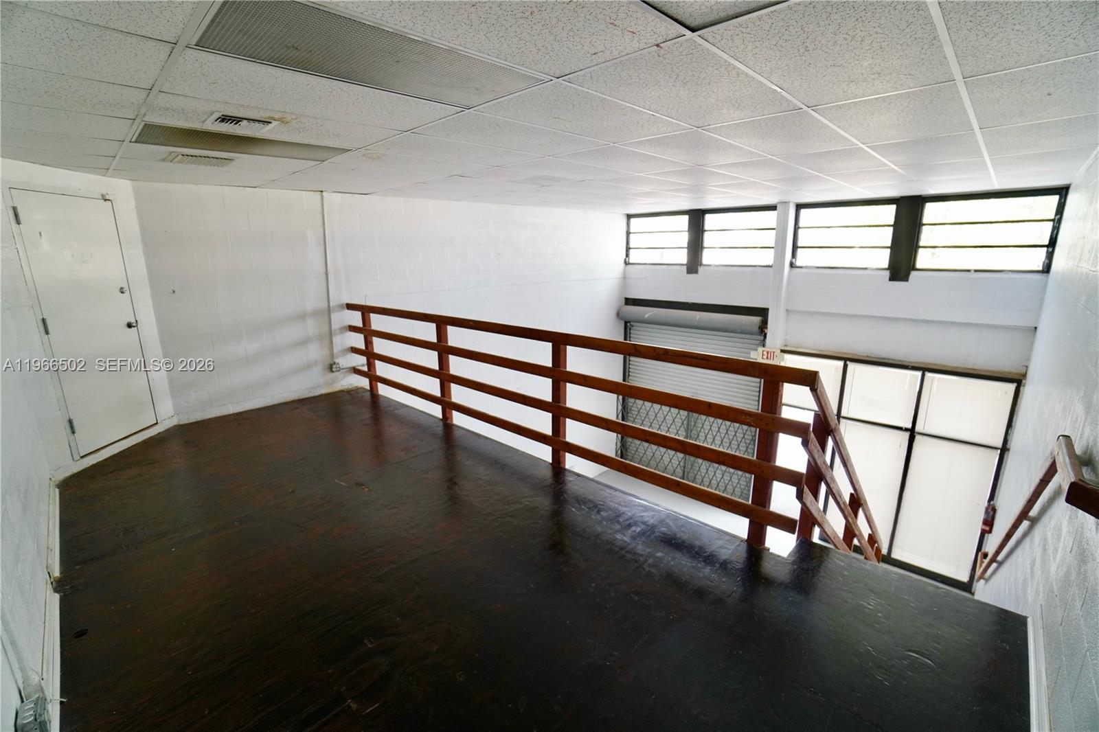 An elevated wooden loft overlooks a lower level with a roll-up door and stairs — 12307 SW 132nd Ct # 4, Miami FL 33186, MIAMI, FL