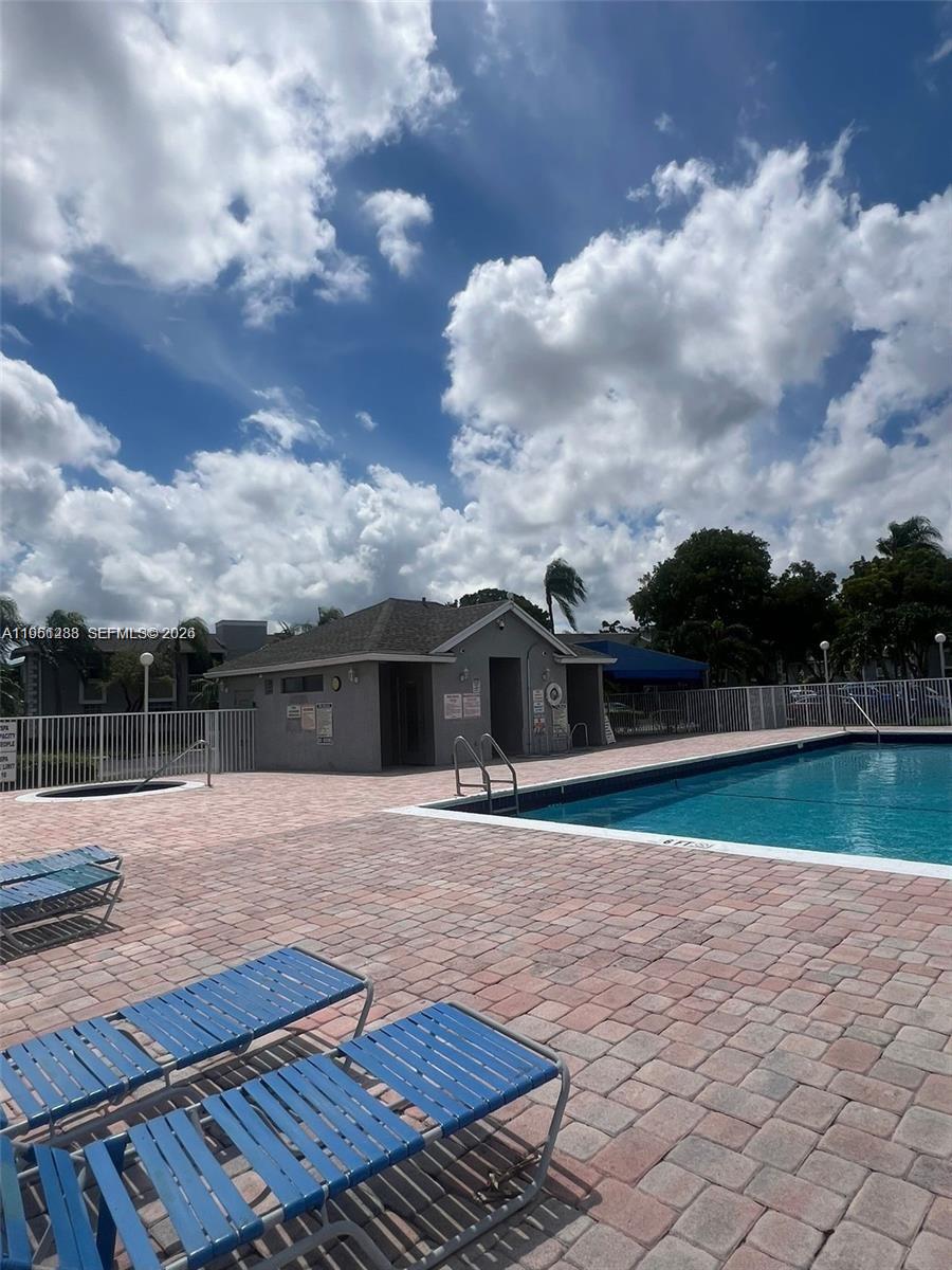 A swimming pool with lounge chairs on a paved deck under a cloudy sky — 455 NE 210th Cir Ter # 18, Miami FL 33179, MIAMI, FL
