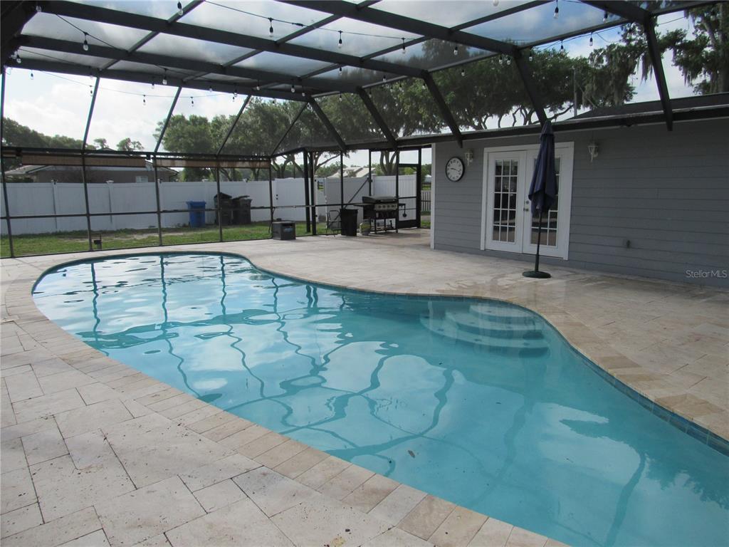 A screened-in patio features a kidney-shaped swimming pool with stone pavers and French doors — 330 MOCCASIN HOLLOW ROAD, LITHIA, FL