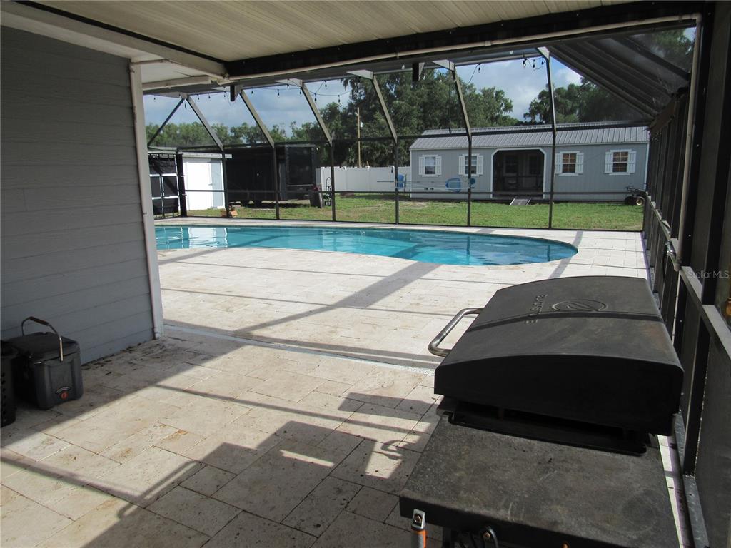A screened-in patio features a swimming pool, a grill, and a view of a shed — 330 MOCCASIN HOLLOW ROAD, LITHIA, FL