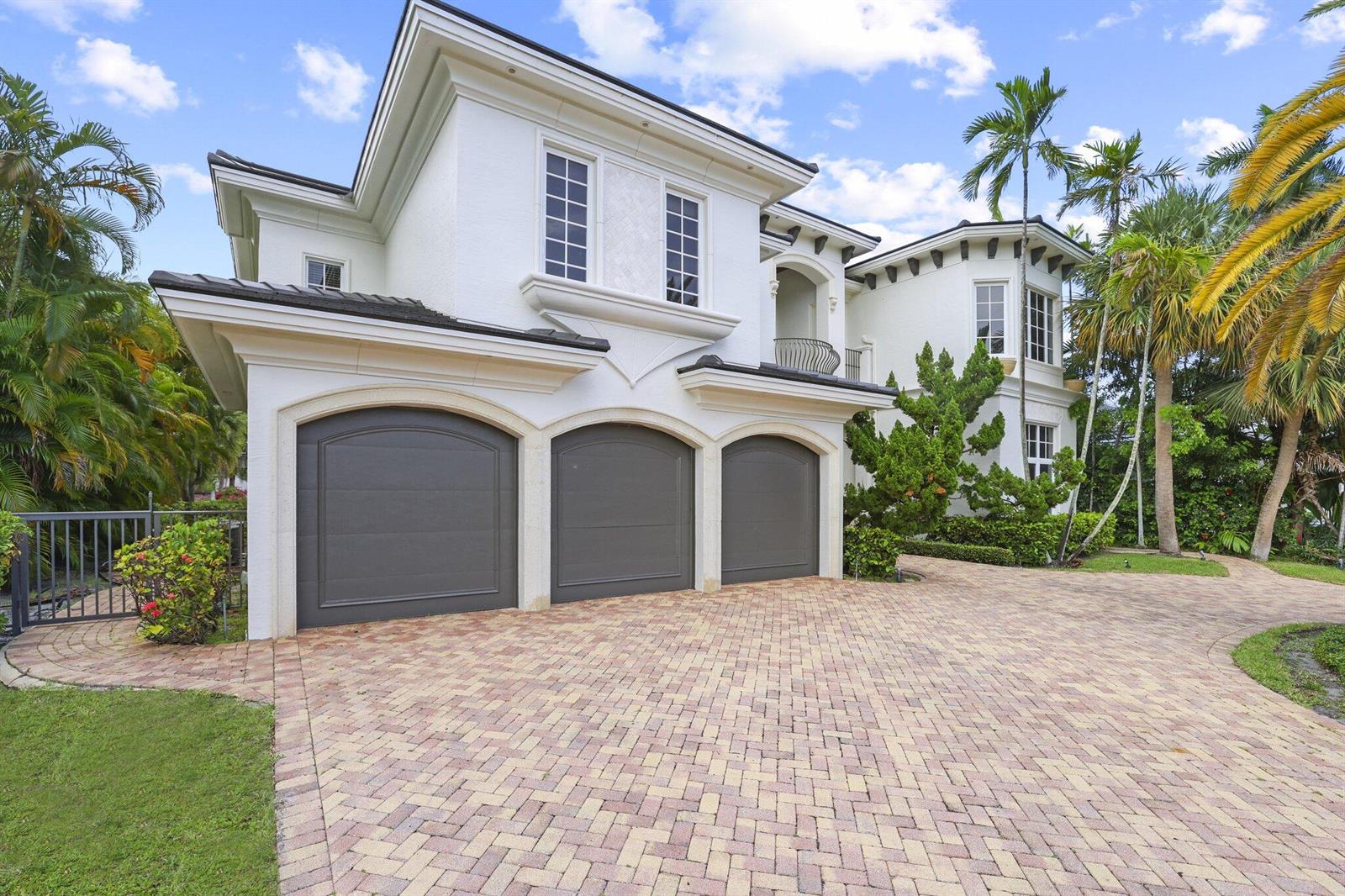 A white two-story house features a three-car garage and a brick paver driveway — 501 Golden Harbour Drive, Boca Raton FL 33432, BOCA RATON, FL