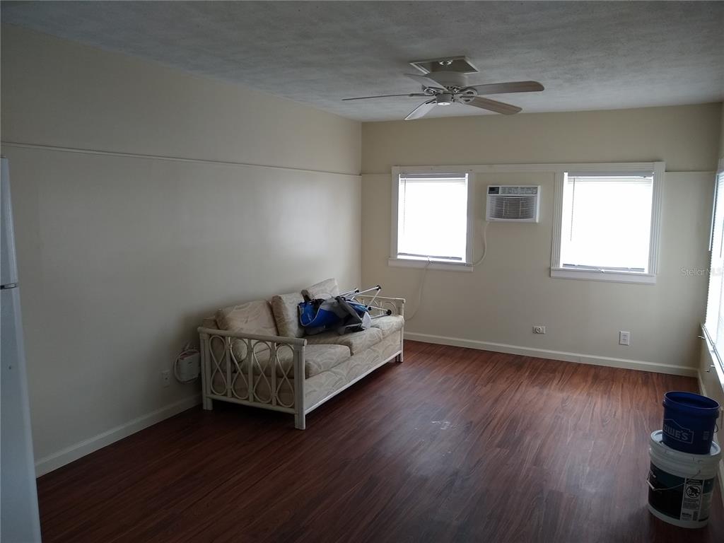 A living room features wood-look flooring, a beige sofa, two windows, and a ceiling fan — 205 52ND AVENUE DRIVE W, BRADENTON, FL