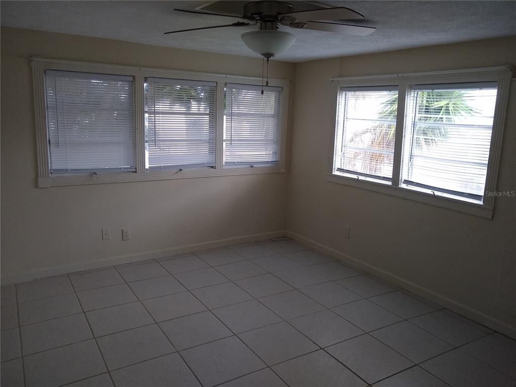 An empty room with white tile floors, a ceiling fan, and multiple windows with blinds — 205 52ND AVENUE DRIVE W, BRADENTON, FL