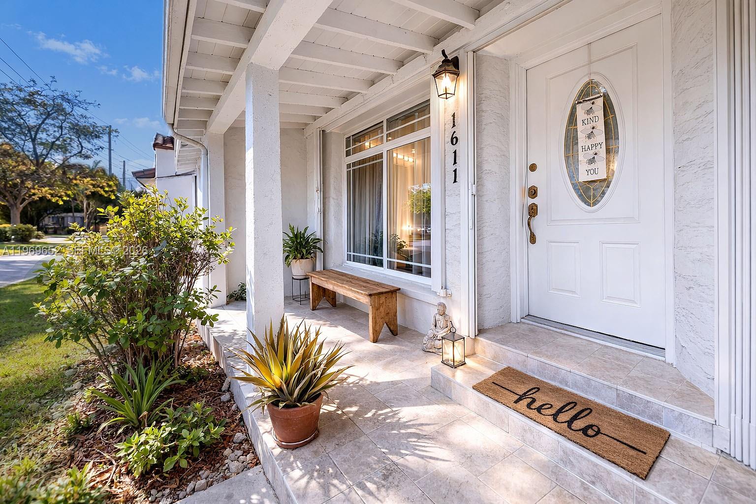 A covered front porch features a wooden bench, a potted plant, and a white door — 1611 SW 21st St, Miami FL 33145, MIAMI, FL
